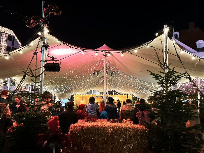 Zwei Kinder sitzen auf einem Strohballen und sehen sich das Programm im Kulturzelt auf dem Alten Markt in Stralsund an.