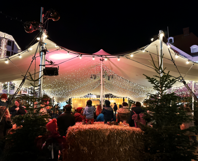 Zwei Kinder sitzen auf einem Strohballen und sehen sich das Programm im Kulturzelt auf dem Alten Markt in Stralsund an.