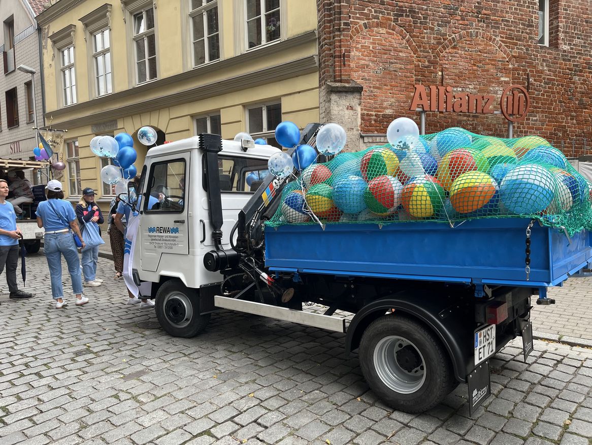 Zu sehen ist ein LKW der REWA Stralsund GmbH mit Wasserbällen auf der Ladefläche